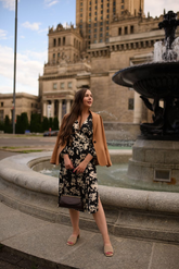 a lady in a black floral printed dress and a brown blazer